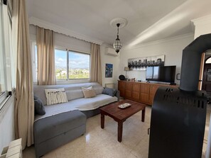 A living room with a sofa, a coffee table, a television, and a grill. - Villa Sandra Top Floor Escape by Casasol by Interhome (Nerja)