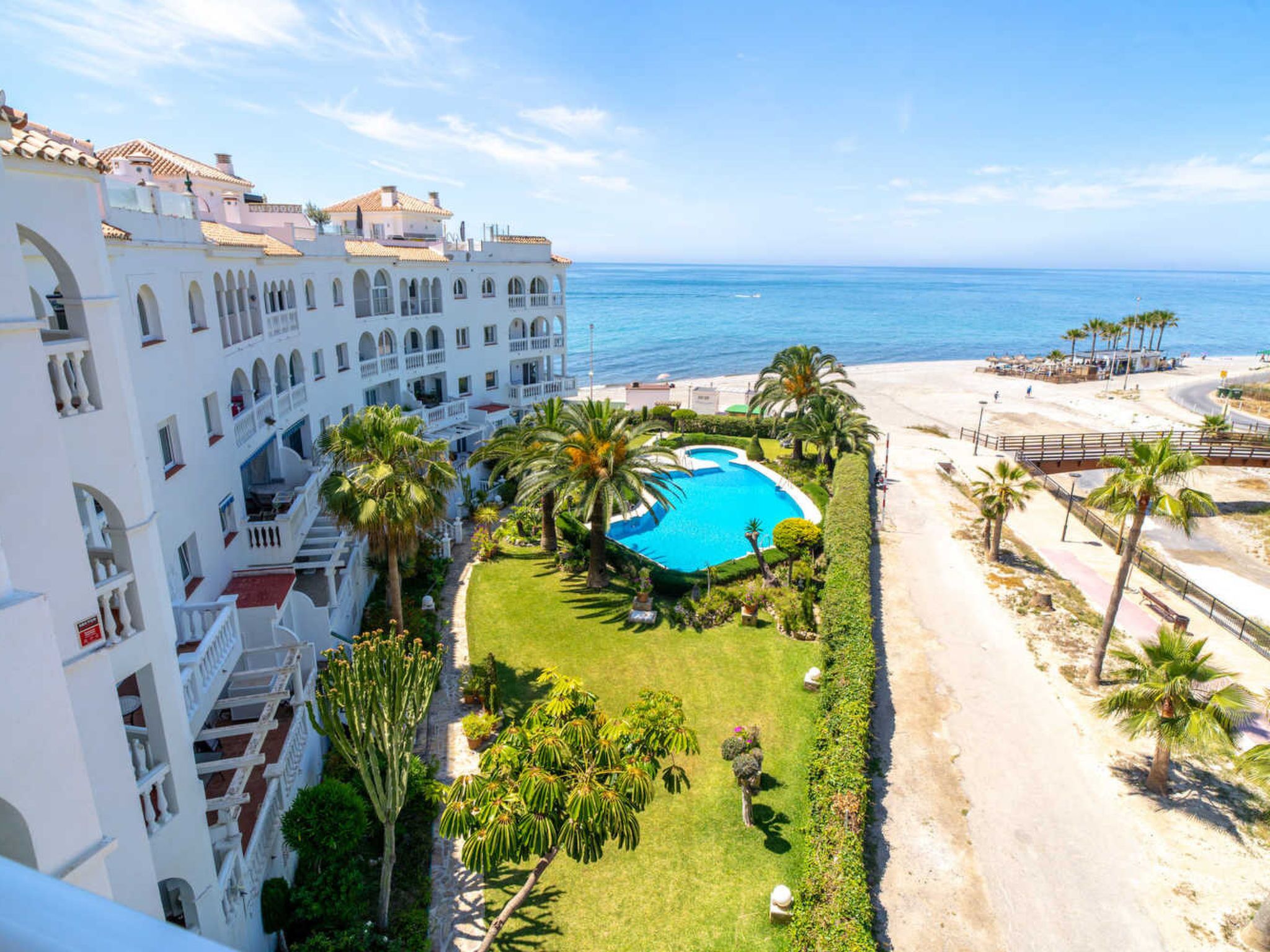 Ein Hotel mit Pool, Palmen und Blick auf den Strand.
