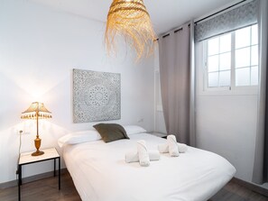 Une chambre moderne avec un lit, une lampe de chevet, un élément décoratif mural et une fenêtre avec des rideaux.