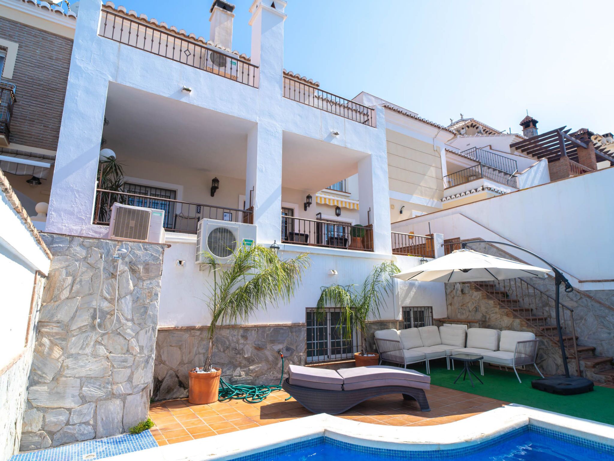 Un edifici residencial de diversos pisos amb una piscina, mobiliari exterior i una escala.