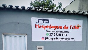 Letrero de 'Hospedagem do Tche' con información de contacto y un nombre de usuario de Instagram.