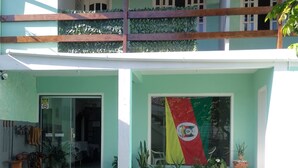 Un edificio con fachada verde, un balcón y una bandera.