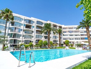 Un hotel con piscina, varios balcones y palmeras.