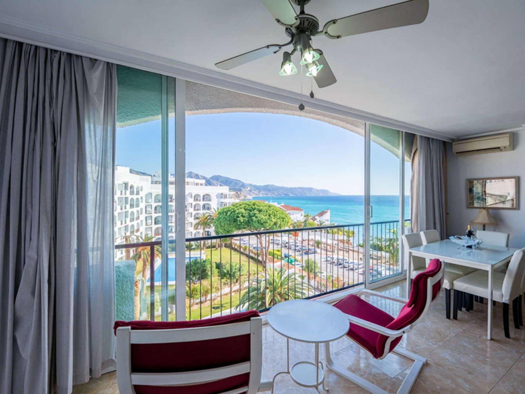A balcony with a view of a resort, a dining area with a table and chairs, and a ceiling fan.