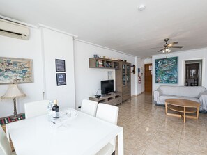 A living room with a dining table, TV, and a ceiling fan. - Apartment  by Interhome (Nerja)
