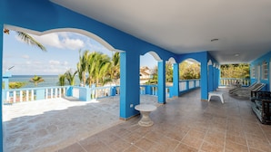 A covered outdoor area with blue pillars, a white table, and a seating area with a view of the sea. - Hotel Pirata Boca de Yuma (Boca de Yuma)