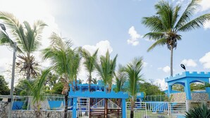 A blue building with a gated entrance, palm trees, and a clear sky. - Hotel Pirata Boca de Yuma (Boca de Yuma)