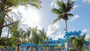 A blue building with a gate, palm trees, and a clear sky. - Hotel Pirata Boca de Yuma (Boca de Yuma)