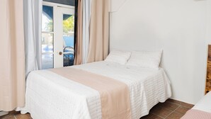 A bedroom with a bed, curtains, and a view of the outside. - Hotel Pirata Boca de Yuma (Boca de Yuma)