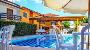 A swimming pool with checkered tiles, white plastic chairs, and umbrellas. - Mestre Lord aparthotel by La Vem Ferias  (Porto Seguro)