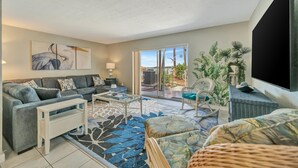 A modern living room with a sofa, coffee table, and a large TV. - Relax Beachside! Tropical Resort Amenities 1B1B (St. Petersburg)