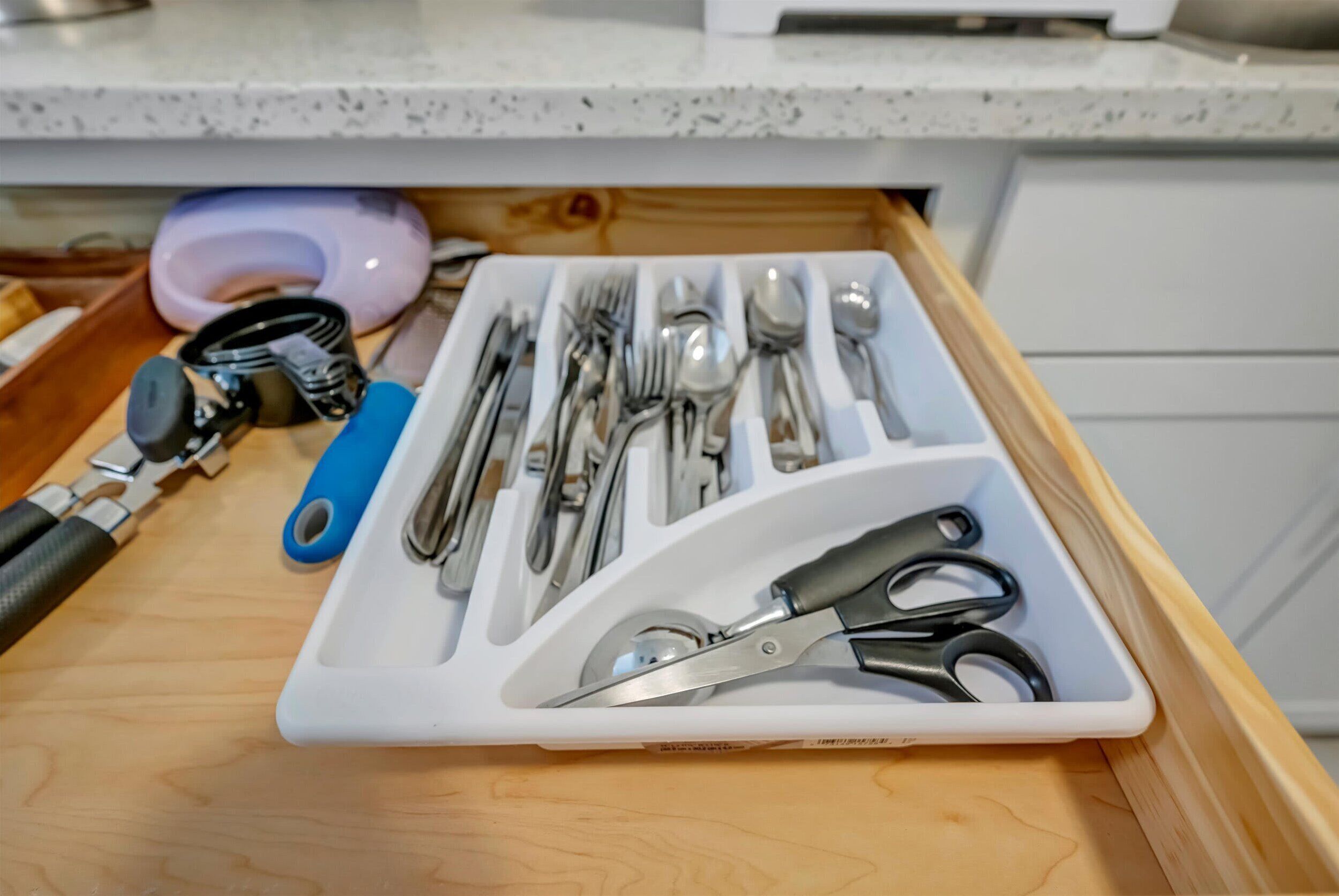 Un cajón con un organizador de utensilios que contiene varias herramientas de cocina.