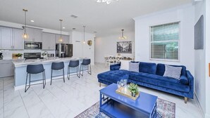 Una cucina moderna con isola centrale, sgabelli da bar e illuminazione a sospensione.