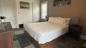 A bedroom with a bed, a ceiling fan, a nightstand, a dresser, a window with blinds, and a cityscape painting on the wall. - Perfect 1-bedroom house in vibrant Minneapolis (Minneapolis)