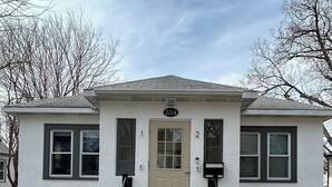 A two-story building with a beige front door, numbered 2214, and a small porch with steps leading up to it. - Perfect 1-bedroom house in vibrant Minneapolis (Minneapolis)