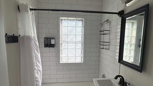 A bathroom with a bathtub, a sink, a toilet, a window with frosted glass, and a shower curtain. - Perfect 1-bedroom house in vibrant Minneapolis (Minneapolis)