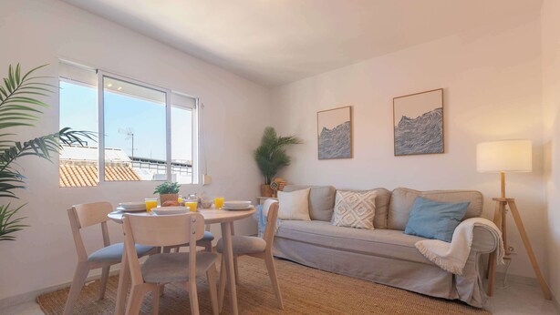 A living room with a sofa, a dining table with chairs, a lamp, and two wall-mounted pictures. - 6th floor Malaga Soho Apartment (Málaga)