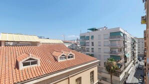 A multi-story building with a red-tiled roof, balconies, and a street view. - 6th floor Malaga Soho Apartment (Málaga)