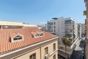 Ein mehrgeschossiges Gebäude mit rotem Ziegeldach, Balkonen und Blick auf die Straße.