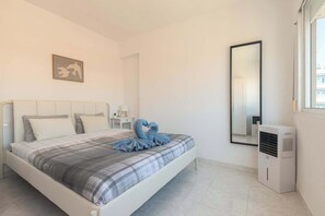 Ein Schlafzimmer mit einem Bett, einem Nachttisch, einem Spiegel und einer Klimaanlage.