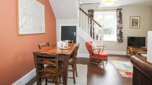 Un espace repas comprenant une table et des chaises en bois, un téléviseur et un escalier menant à un niveau supérieur.