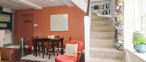 A staircase with carpeted steps, a dining area with a wooden table and chairs, and a bookshelf against the wall.