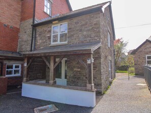 A stone building with a porch, a window, and a door. - Little Pentwyn (Hereford)