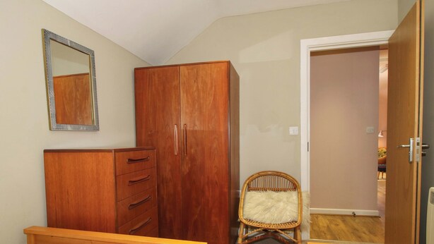 Een slaapkamer met een kledingkast, een spiegel, een stoel en een bed met handdoeken.