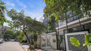 A residential building with a gated entrance, a balcony, and a large window with a leaf pattern. - Cam On Luxury Pool 4BR Villa by the Beach (Da Nang)