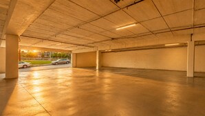 Eine Tiefgarage mit Betonböden und -wänden, einige geparkte Autos und freie Sicht auf die Straße.