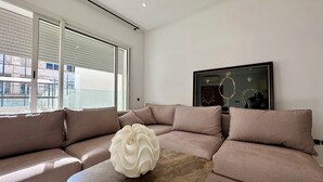 Una sala moderna con un sofá modular, una mesa de centro de mármol y una obra de arte enmarcada en la pared.
