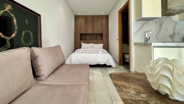 Una habitación de hotel moderna con una cama, un sofá, un baño de mármol y una pared de acento de madera.