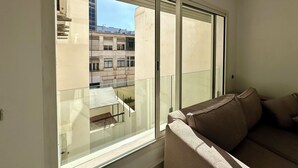 Una habitación con un ventanal grande, un sofá y vistas a edificios.