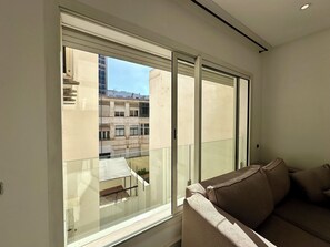 A room with a large window, a sofa, and a view of buildings outside. - Modern studio Anfa center (Casablanca)