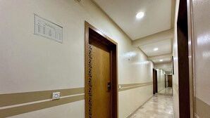 Un pasillo de hotel con una puerta de madera, suelo de mármol y un cartel en la pared.