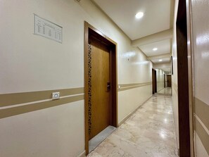 A hotel hallway with a wooden door, a marble floor, and a sign on the wall. - Modern studio Anfa center (Casablanca)