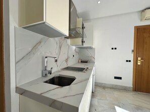 A modern kitchen with a marble countertop, a sink, and a built-in oven. - Modern studio Anfa center (Casablanca)