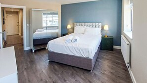 A bedroom with a large bed, bedside lamps, and a view through a window. - Harbour View Apartments Portsmouth (Portsmouth)