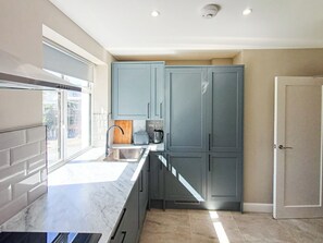 Una cocina moderna con gabinetes grises, encimera de mármol y una ventana.
