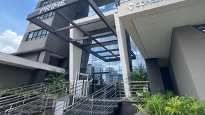 A modern building with 'PRIME' and 'CONSBASE' signage, featuring a prominent staircase and glass facade. - Cozy Apartment - Prime Building (Campo Grande)