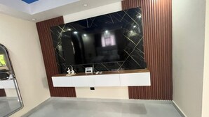 A modern room with a large wall-mounted TV, wooden paneling, and a white console table.