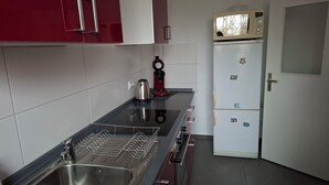 A kitchen with a stainless steel sink, a kettle, a microwave, and a refrigerator. - Room "grey" in shared flat - central and quiet - VW, Autostadt, VfL parking lot and WLAN (Wolfsburg)