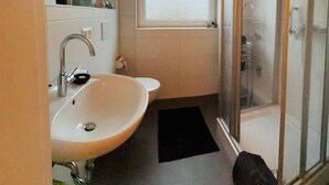 A bathroom with a sink, toilet, window, and glass shower enclosure. - Room "grey" in shared flat - central and quiet - VW, Autostadt, VfL parking lot and WLAN (Wolfsburg)