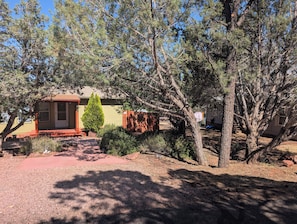 A residential property with a single-story house, a front yard with a red pathway, and a large tree.