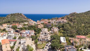 Una località costiera con edifici a terrazze, vista sul mare e uno sfondo collinare.