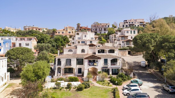 Una zona residenziale su una collina con edifici a più piani, una strada asfaltata e auto parcheggiate.