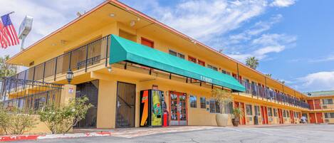 A motel with a yellow facade, a green awning, and a flag.