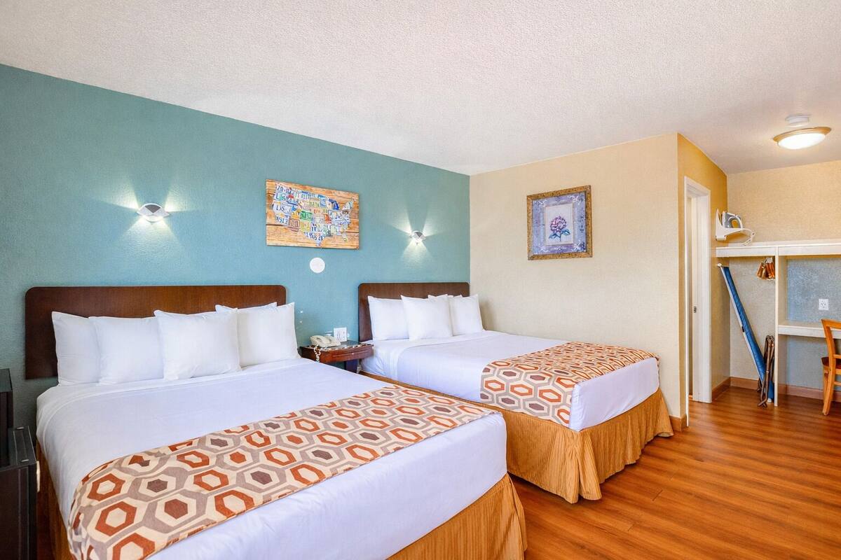 A hotel room with two beds, a desk, and a chair.