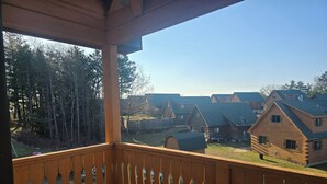 A wooden deck with a view of a residential area. - The Green Bear Cabin (Unit A) Near Jellystone/Three Bears Resort in Warrens, WI (Warrens)