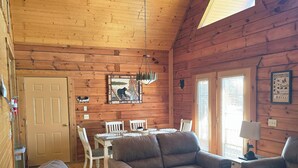 A cozy cabin interior with wooden walls, a dining area, and a fireplace. - The Green Bear Cabin (Unit A) Near Jellystone/Three Bears Resort in Warrens, WI (Warrens)